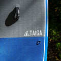 Close-up of a gray and blue paddle board mat with 'TAIGA' branding.