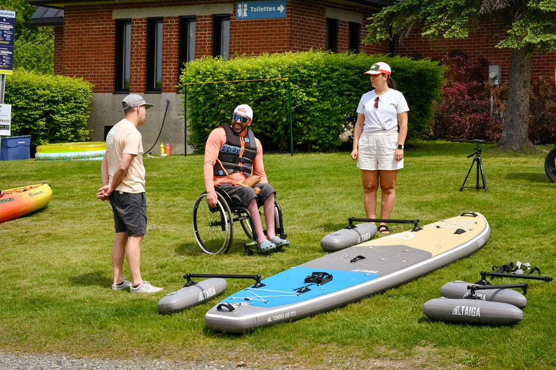 3 persons near the TAIGA Adaptive SUP on the grass