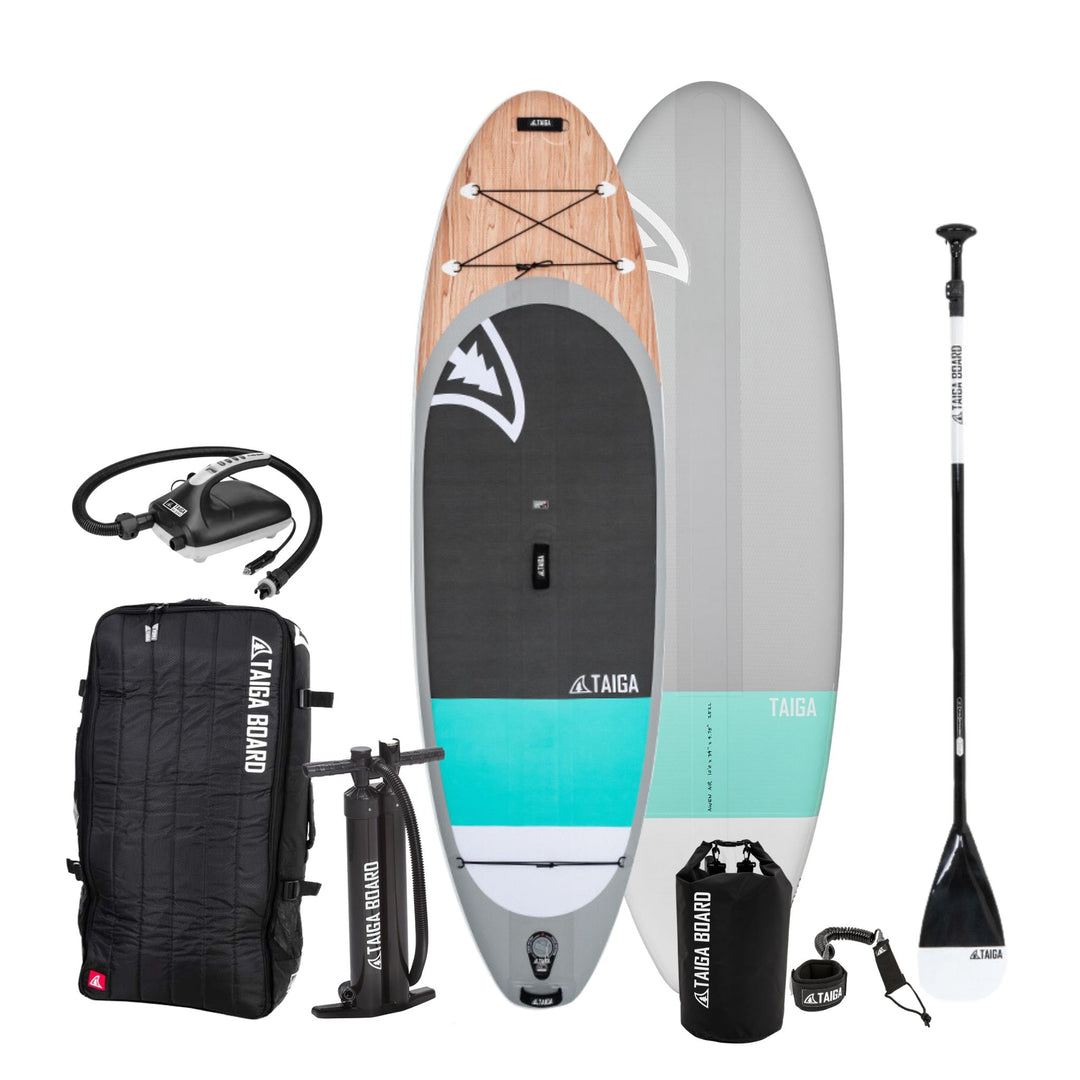Taiga inflatable stand-up paddle board package including a paddle board, a black Taiga Board Bag, a hand pump, a leash, an electric pump, a dry bag and a paddle on a white background.