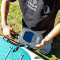 Person holding a TAIGA board pump near a paddleboard