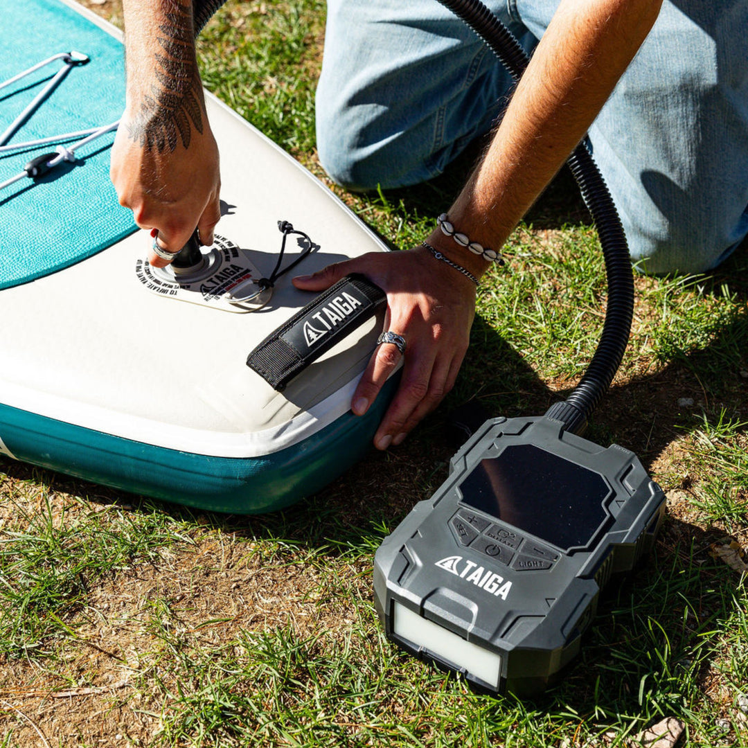 Person inflating a paddleboard with a Taiga pump