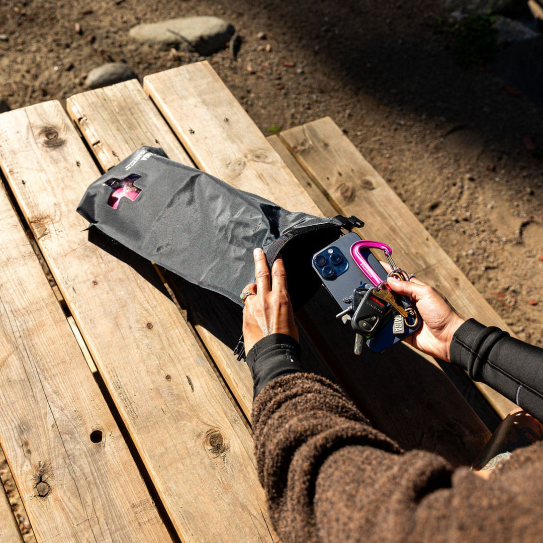 Person packing a black dry bag with keys and phone