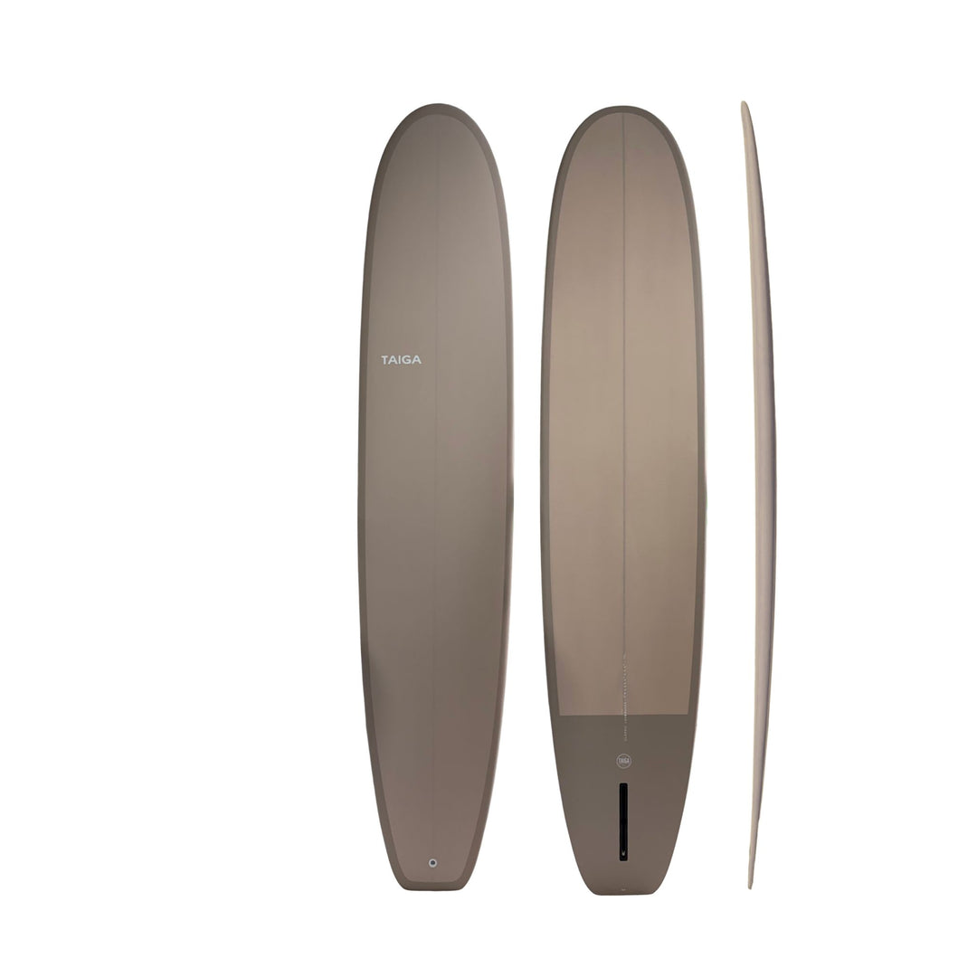 Three views of a Taiga surfboard in a warm taupe-brown color, showing the top, bottom, and side profiles against a solid white background.