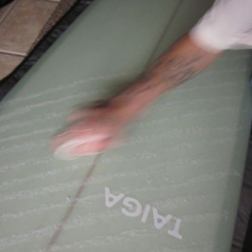 Person waxing a green surfboard