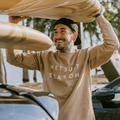 Man wearing the WETSUIT SEASON CREWNECK - SAND