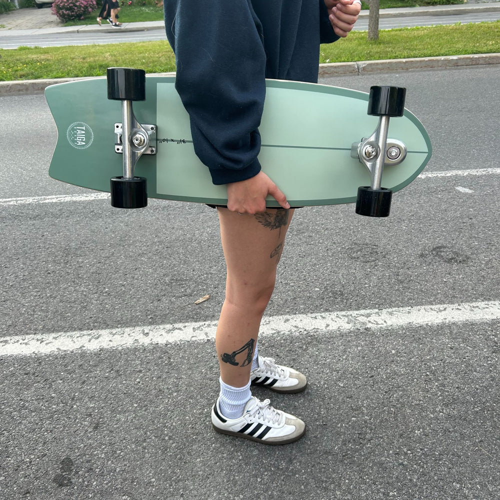 Skater Holding The Dusty Sage Surfskate On a Street