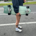 Skater Holding The Dusty Sage Surfskate On a Street