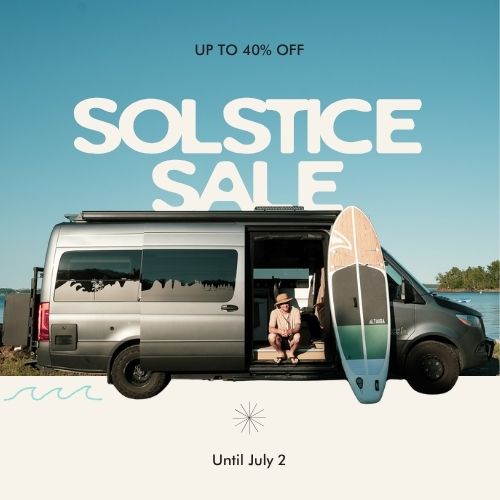 Van with open door, person sitting inside, and paddleboard on a beach with 'Solstice Sale' text overlay.