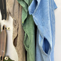 Three ponchos slits in different colors hanging on a wall with two skateboards below.
