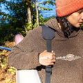 Person using a shoulder strap to carry an inflatable paddle board
