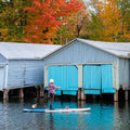 Paddler on an inflatable SUP near boat houses in fall