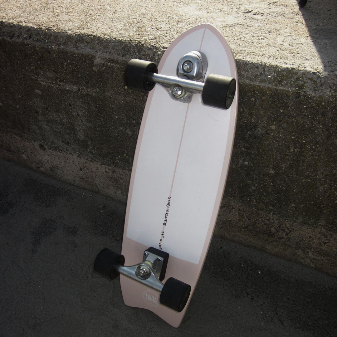 Skateboard leaning against a concrete wall on a street.