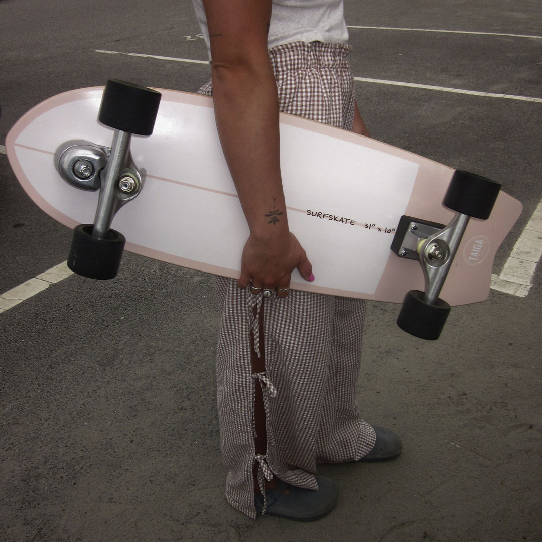 Person holding a pink skateboard in an outdoor setting