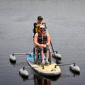 Two people on a paddleboard with one in a wheelchair, on a calm body of water.