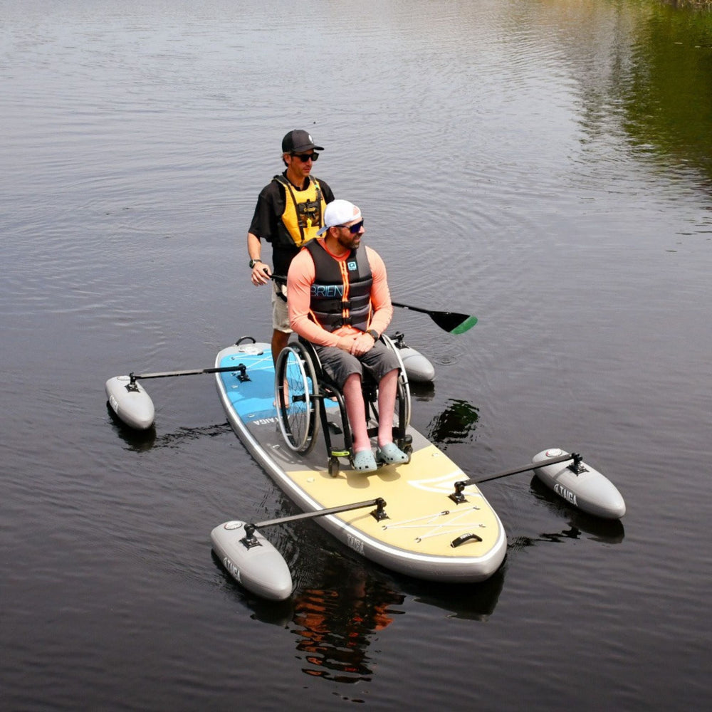 Two people on an Adaptive Inflatable Paddle Board with stabilizers in calm water.