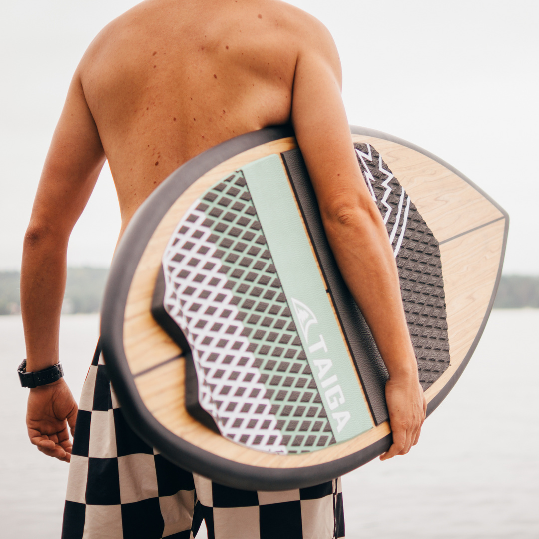 Surfer boy holding the Carbon Black Skim 4'8 - Wakesurf from TAIGA